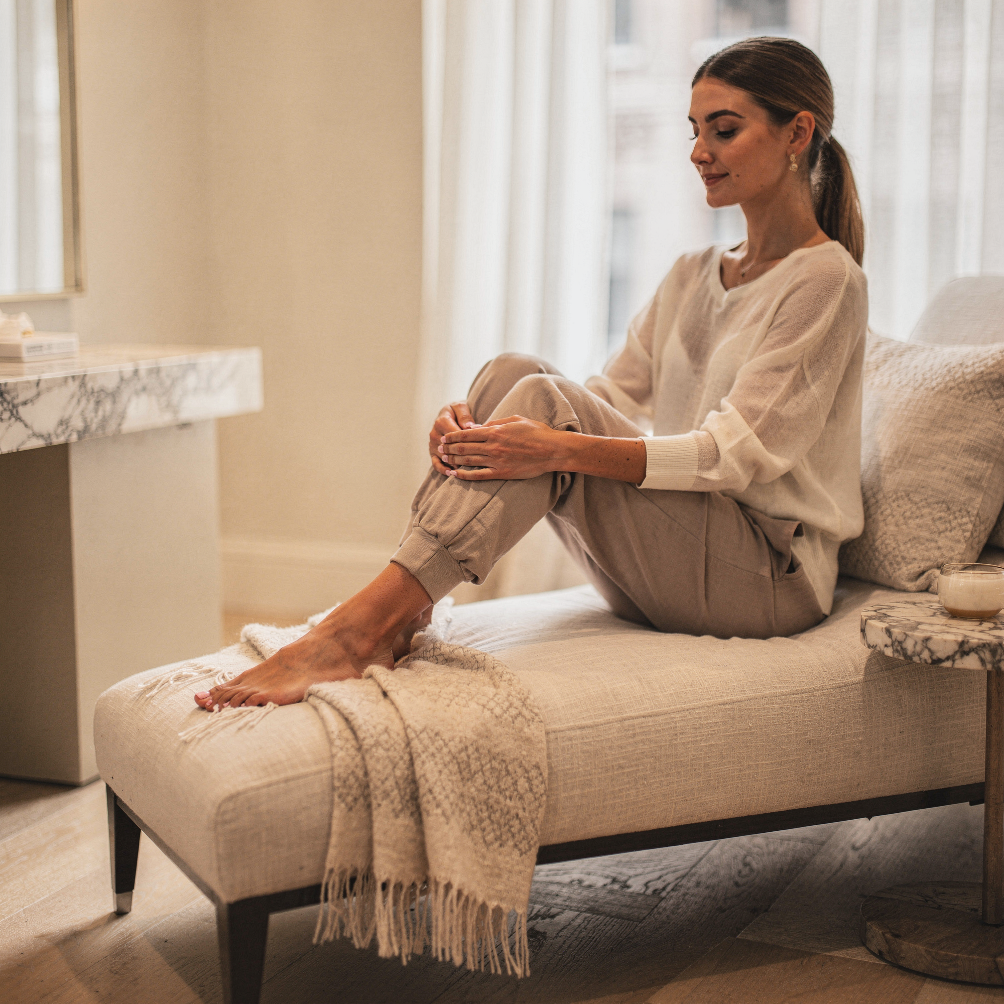 Woman sitting on a couch examining her foot and ankle